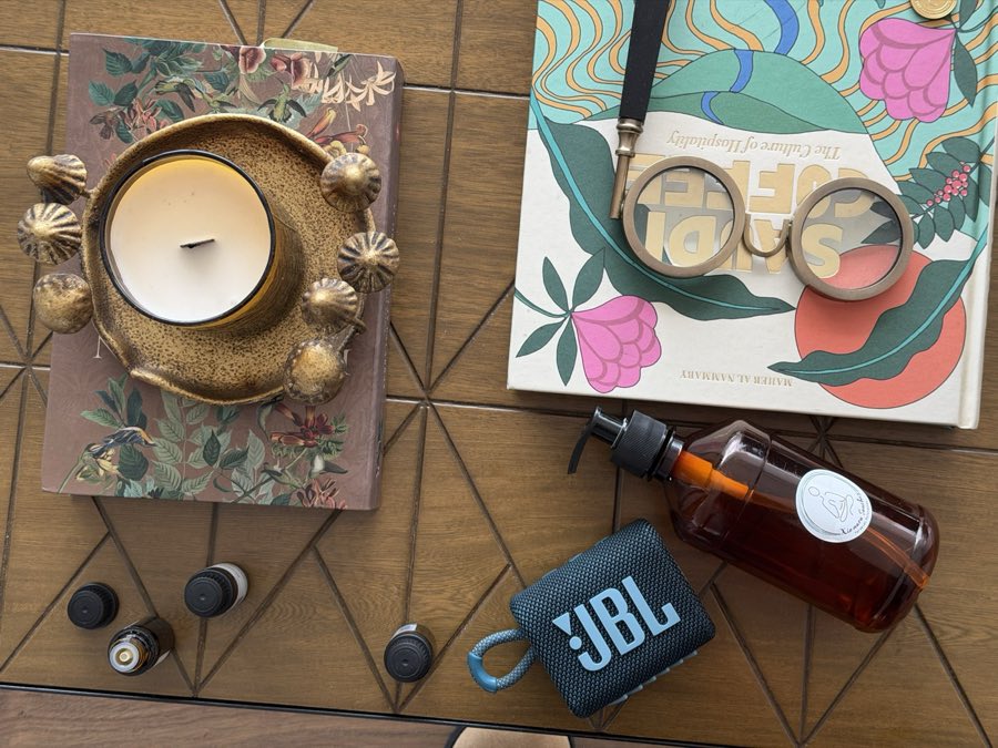 Vela, cuenco y frascos de aceite dispuestos sobre una mesa de madera.